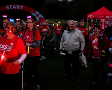 Group of walkers taking part in charity walk at night wearing glowing accessories