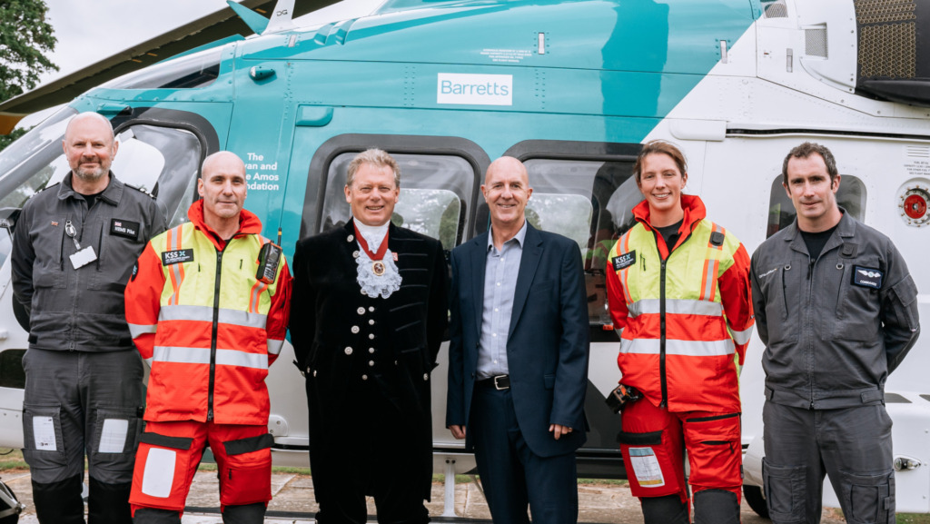 5 people in front of stationary helicopter, facing camera
