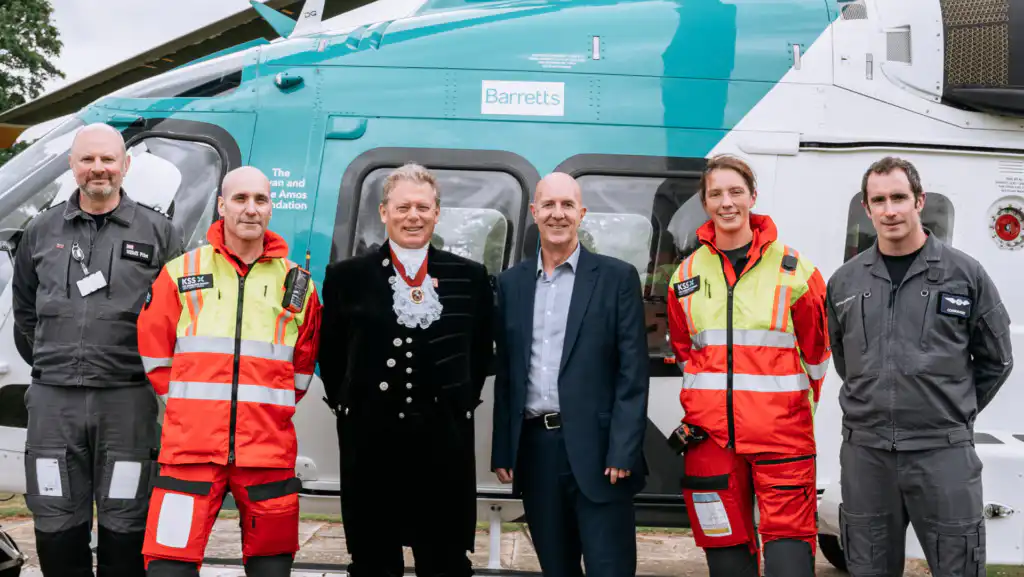 5 people in front of stationary helicopter, facing camera