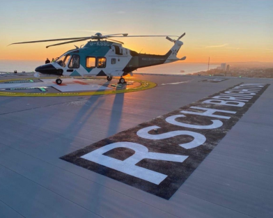 Air ambulance helicopter on hospital rooftop helipad with setting sun and the sea in the background