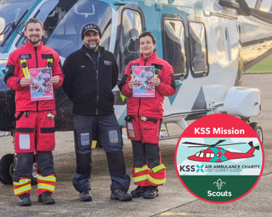Three air ambulance crew members in front of helicopter facing the camera and holding booklets. An image of the KSS Mission Badge is superimposed over the photograph.