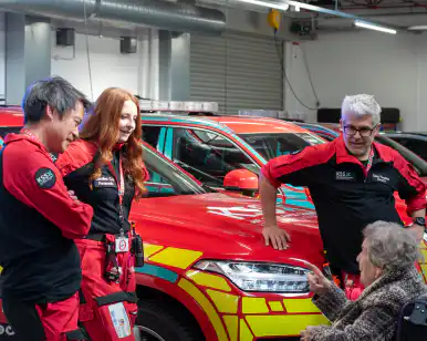 Lady in wheelchair talking to air ambulance crew with rapid response vehicles in background