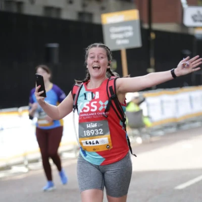 Lady running with arms out and wide smile.